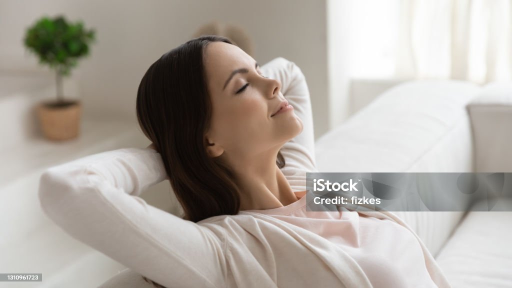 Tranquil millennial female napping on couch with hands behind head Weekend, at least!.. Tranquil peaceful millennial female enjoying freedom napping dreaming relaxing on couch with closed eyes and hands behind head meditating breathing fresh air feeling happy serene Clean Stock Photo