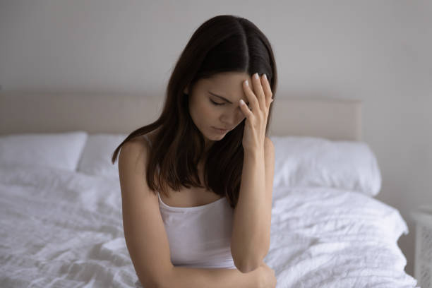istock Frustrated young woman sitting on bed suffering from sudden headache 1310961783