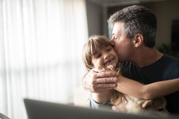 ojciec obejmując i całując córkę podczas pracy w domu - kissing child family isolated zdjęcia i obrazy z banku zdjęć