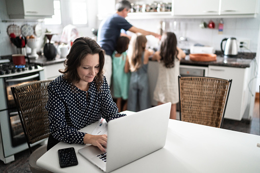 Mature woman working with family in the background at home