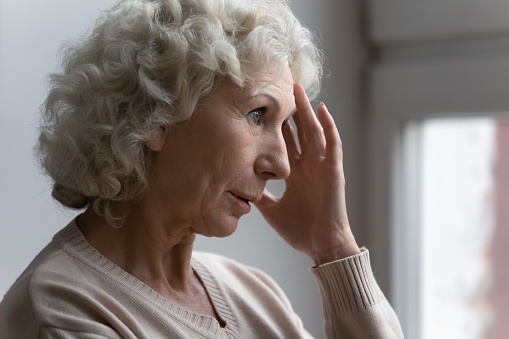 Confused worried old lady suffering from age disorders, Alzheimer disease, headache. Concerned pensive senior 70s woman feeling anxiety, losing memory, having mental disease symptoms. Close up