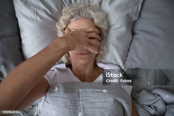 Peaceful Sleepy Senior Woman Awaking In Her Bed Stock Photo - Download Image Now - Insomnia, Sleeping, Senior Adult
