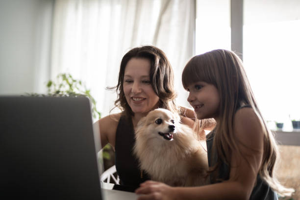 madre che tiene cane e lavora a casa con la figlia - spitz type dog immagine foto e immagini stock