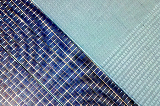 Aerial view of surface of blue photovoltaic solar panels mounted on building roof for producing clean ecological electricity. Production of renewable energy concept.