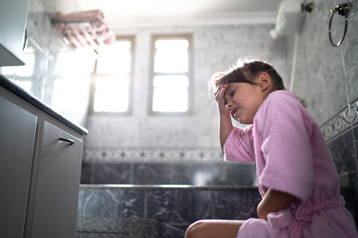 Chica con dolor de estómago usando el inodoro en casa photo