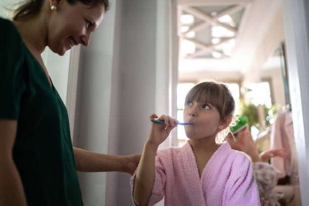 istock Mother watching daughter brushing teeth at home 1310962393