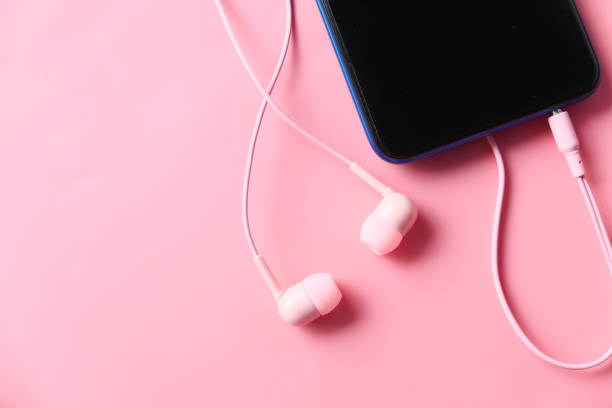 istock smart phone and pink color ear phone on pink background . 1310963360
