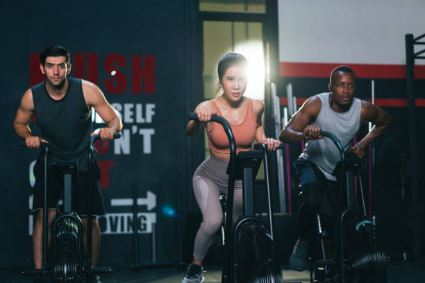 gruppo multietnico di sportivi che si allena sulla macchina da spinning bike in palestra fitness - spinning health club instructor gym foto e immagini stock