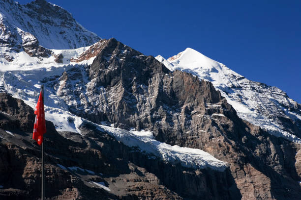 el cono blanco del silberhorn que se eleva sobre el valle de trümmeltal, de kleine scheidegg, con la bandera suiza en primer plano: oberland bernés, suiza - silberhorn fotografías e imágenes de stock