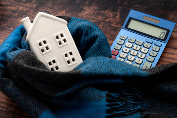 Warming efficiency of a residence and calculate heating costs concept with digital calculator, small house wrapped in warm wool neck scarf on wood background Warming efficiency of a residence and calculate heating costs concept with digital calculator, small house wrapped in warm wool neck scarf on wood background energy bill photos stock pictures, royalty-free photos & images