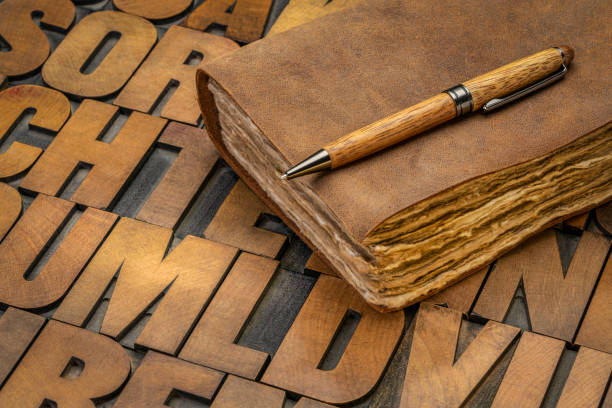 retro leatherbound journal or book with decked edge handmade paper pages and a stylish pen on a letterpress wood type alphabet, journaling concept