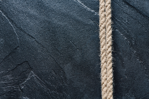 Two pieces of hemp rope lying parallel on slate textured surface