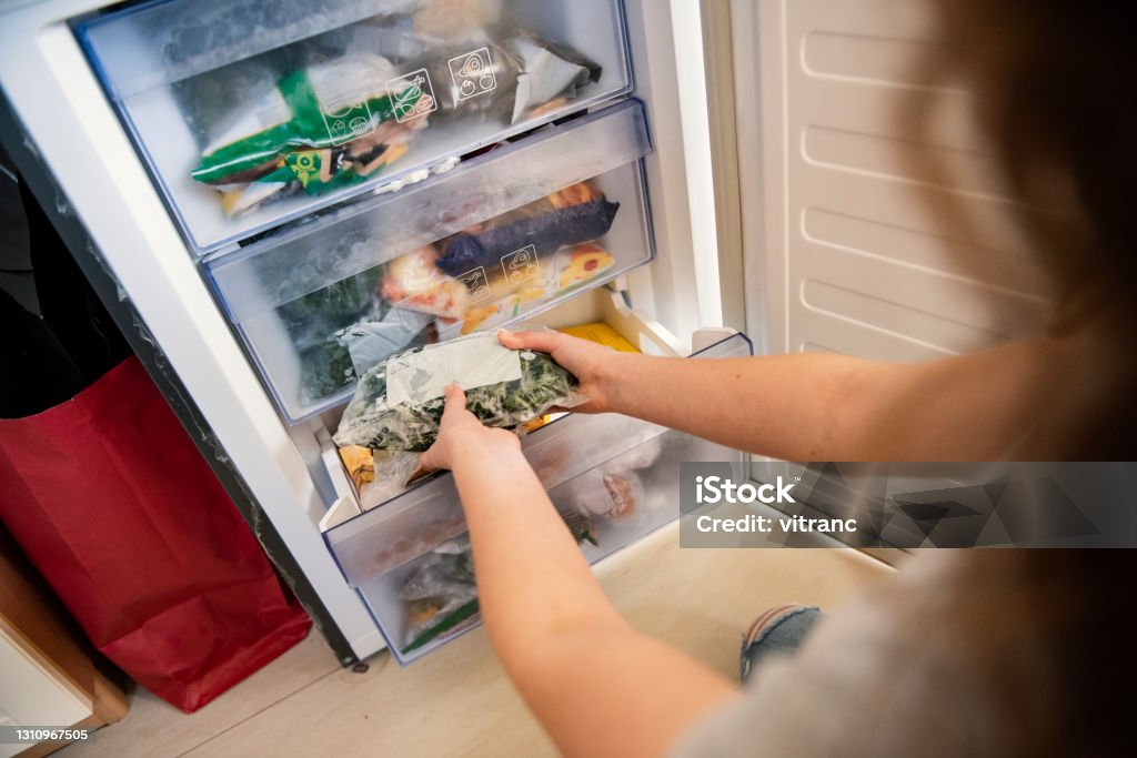 Meisje dat ruw voedsel van koelkast neemt - Royalty-free Diepvries Stockfoto