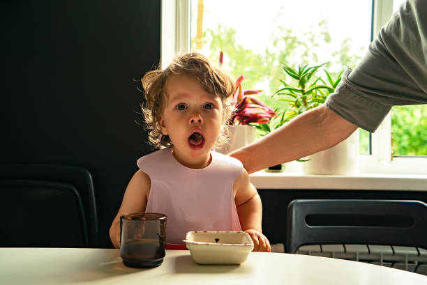 Small child choked on food eating in the kitchen indoors Portrait of a small child choked on food eating in the kitchen and a parent slaps his hand on the back choking stock pictures, royalty-free photos & images