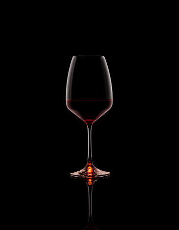 Glas of red wine against a black background with reflection