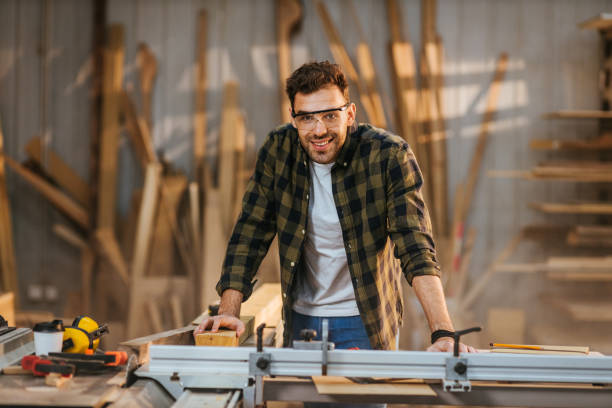 Portrait of a smiling carpenter in the workshop Portrait of a carpenter standing in front of the machines in the workshop. carpenter portrait stock pictures, royalty-free photos & images