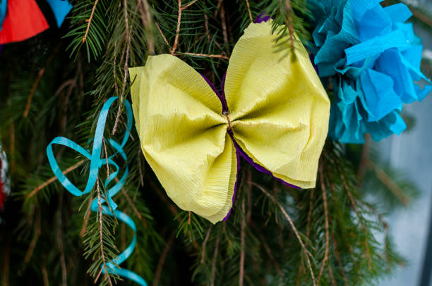 istock Yellow bow with blue ribbons on the green pine tree 1310977131
