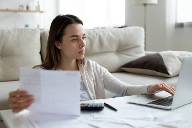 istock Focused young woman using laptop, checking financial documents at home 1310977328