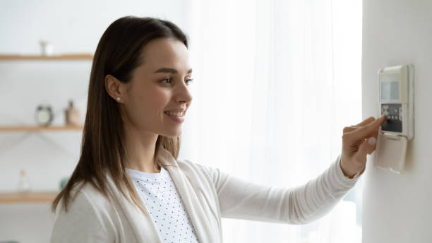 istock Smiling young woman pressing buttons on smart house system 1310977365