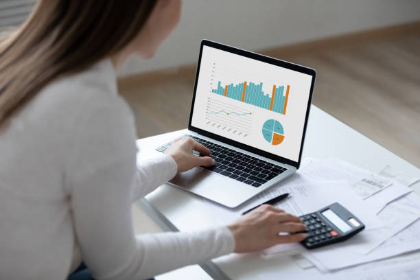 istock Close up young woman using laptop, working with financial documents 1310977370