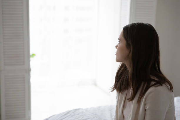 istock Woman sitting on bed looking at window in low spirit 1310977409