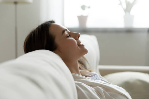 istock Close up smiling young woman leaning back on cozy couch 1310977436