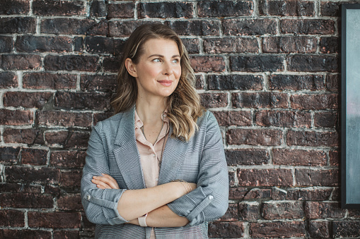 Mature business woman portrait. She is standing next to do wall and posing.