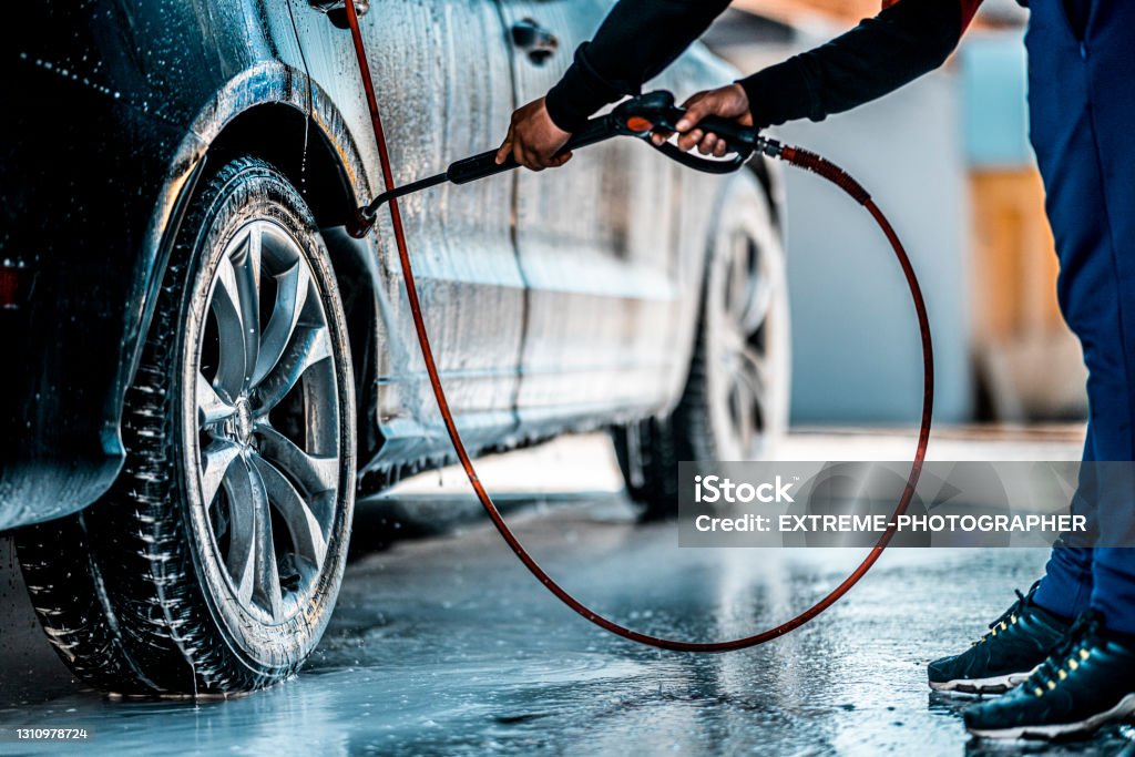The washing process on a self service car wash Washing wheel arch with a jet of water in a self service car wash. Car Wash Stock Photo