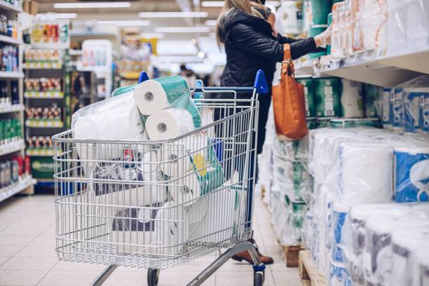 Woman shopping at supermarket choosing toilet paper. stock photo