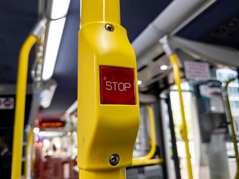 Close up focus on a red 'Stop' button inside a metro bus in Seattle, WA