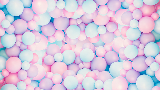 Design concept. Lots of multi colored balls or marbles lay together in a heap. They have pastel colors that are mixed together like  pink, light blue, yellow and light green.