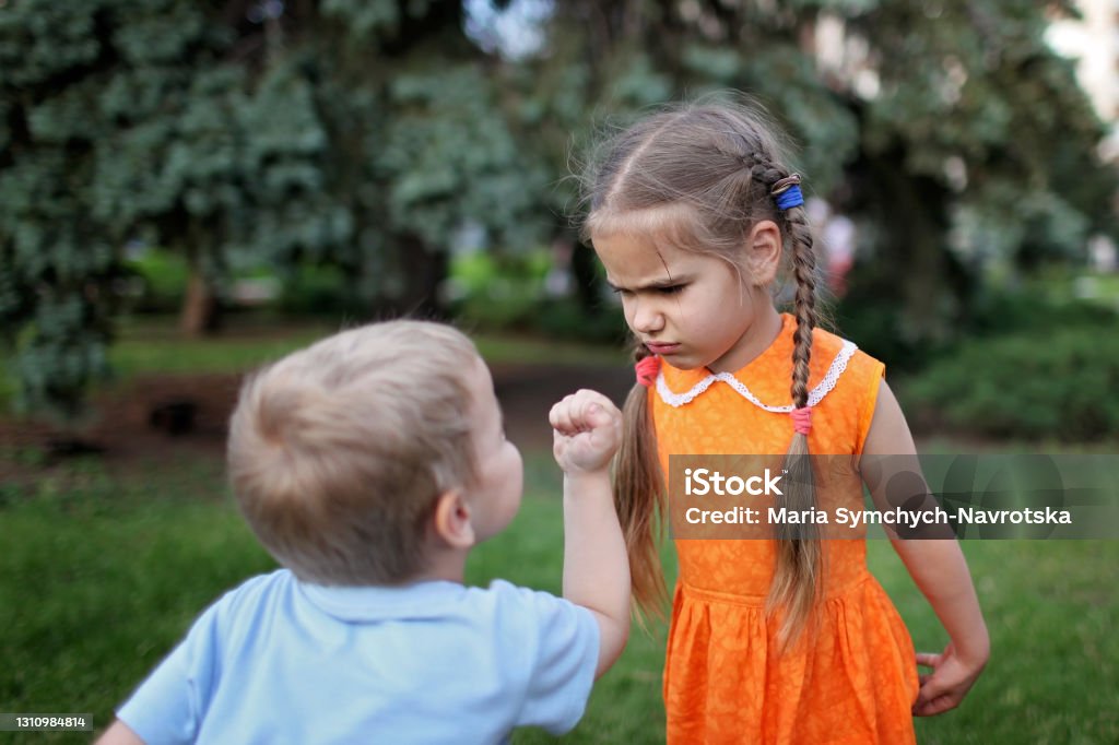 Kid negative emotions Two little children, sister and brother, quarreling and ready to bit each other crying during their walking, bad mood, negative emotion, upbringing and family concept, summer outdoor Arguing Stock Photo