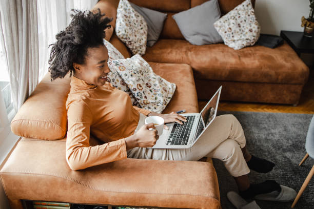 istock Young African American woman is working from home on laptop while drinking coffee 1310986246