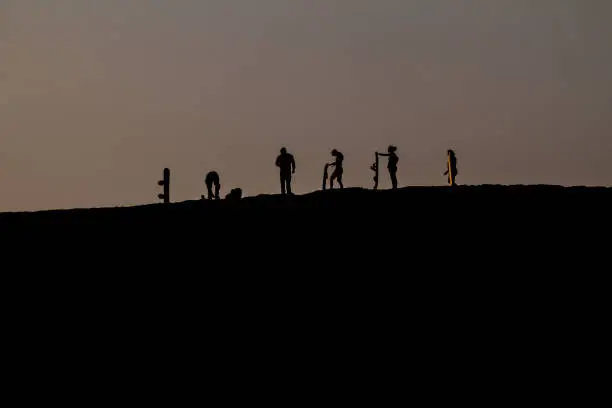 Silhouettes of sand boarders during the sunset near desert oasis Huacachina near Ica, Peru