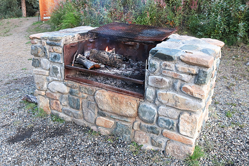 A large stone outdoor grill with a fire burning.