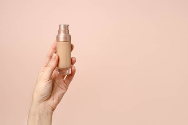 istock Hand holding makeup liquid found, Applying foundation for makeup. Woman's hands with neutral manicure holding bottle of concealer or toner foundation, copy space, banner, flyer 1311011196