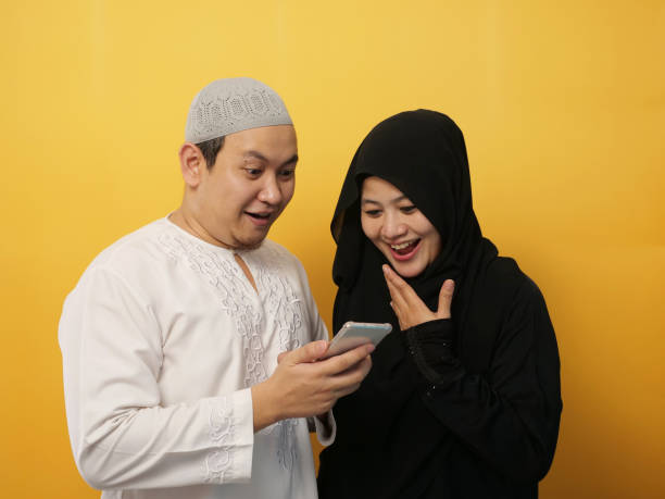 Asian muslim couple shocked or surprised to see something on smart phone, happy expression winning gesture Portrait of Asian muslim couple shocked or surprised to see something on smart phone, happy expression winning gesture malay couple stock pictures, royalty-free photos & images