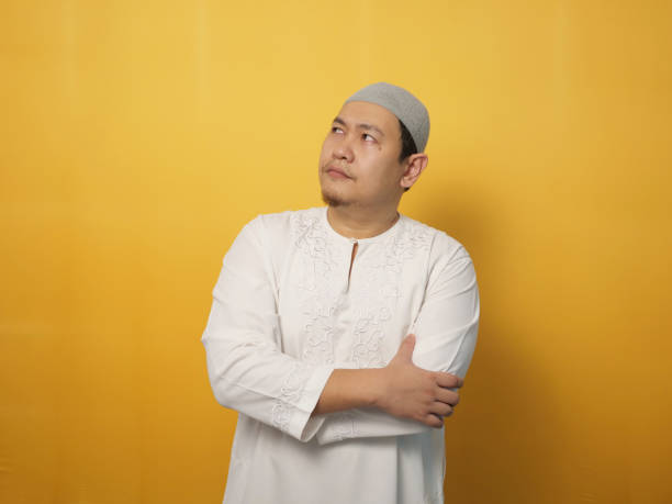 istock Asian muslim man shows thinking contemplating expression. Looking for solution of a problem. Close up portrait against yellow 1311011353