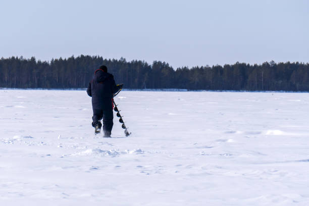 istock fisherman on a winter lake drills the ice with a motor drill 1311017619