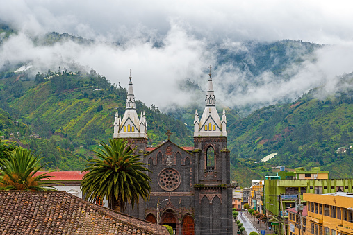 Aerial cityscape of Banos de Agua Santa located in the cloud forest with the bell towers of the Holy Water Virgin Church, Ecuador.