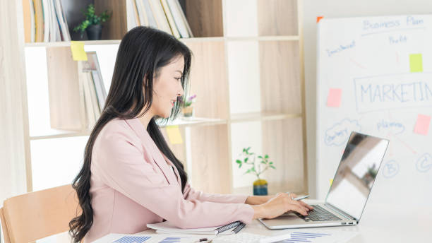 istock A beautiful Asian businesswoman works with documents, graphs, analyzes, and uses a laptop to work from home to create a social distance. 1311021976