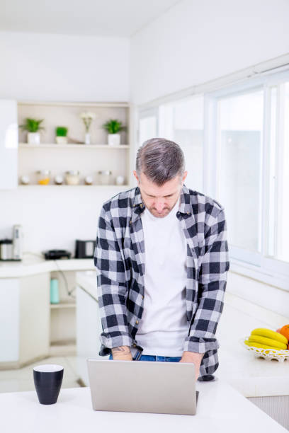 istock Mature man using a laptop in the kitchen 1311024899