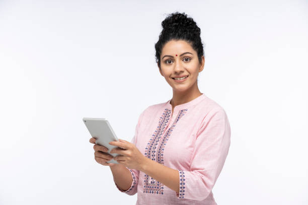 portrait of a young women using digital tablet standing isolated over white background:- stock photo - kurta imagens e fotografias de stock