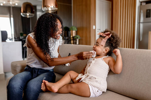 istock Mother using makeup remover on her daughter sitting on the sofa 1311033007