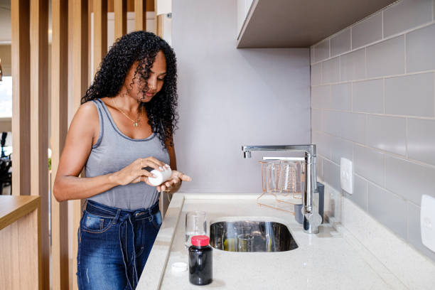 istock Beautiful black woman taking vitamins in the kitchen 1311033014