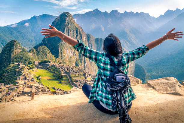 A woman tourist contemplating the amazing landscape of Machu Picchu with arms open A woman tourist contemplating the amazing landscape of Machu Picchu with arms open. Archaeological site, UNESCO World Heritage machu picchu stock pictures, royalty-free photos & images