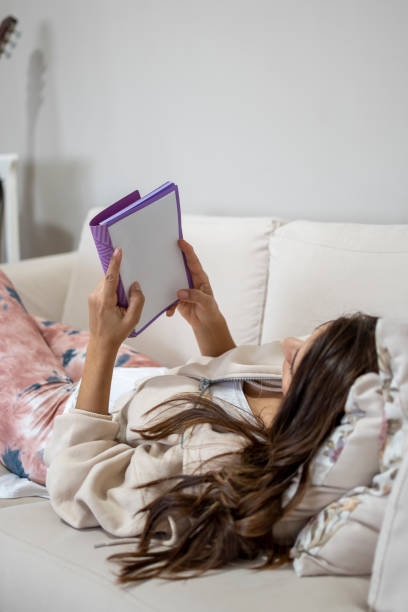 istock Woman reading book at home 1311034140