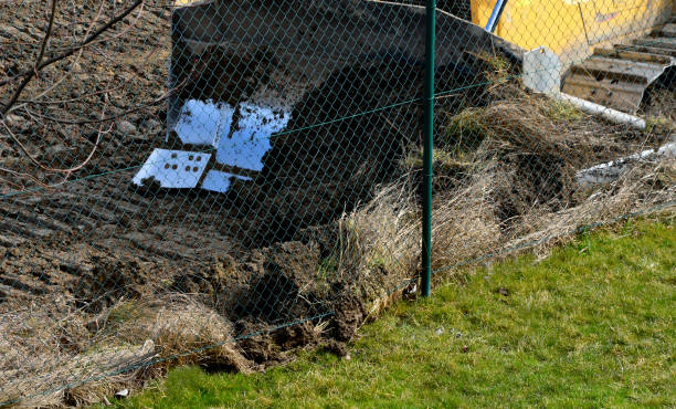 istock bulldozer performs topsoil raking. the land behind the wire fence is now a construction site de the lawn disappears and there is only a pile of soil and heavy construction equipment. The excavator pushes the soil in front of him into a pile 1311036165