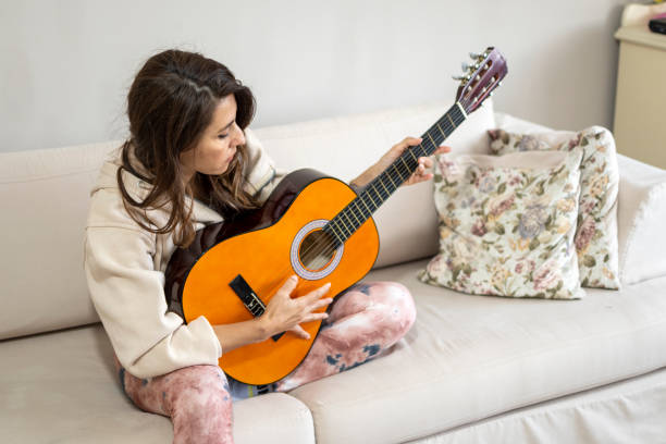 istock Woman playing guitar at home 1311037830