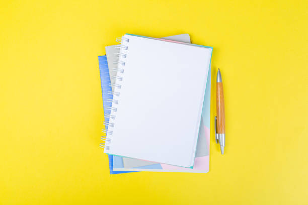 istock open spiral notepad on a yellow background with a pen. top view, stack of notepad with blank sheet. school concept, businessman work desk. 1311039793